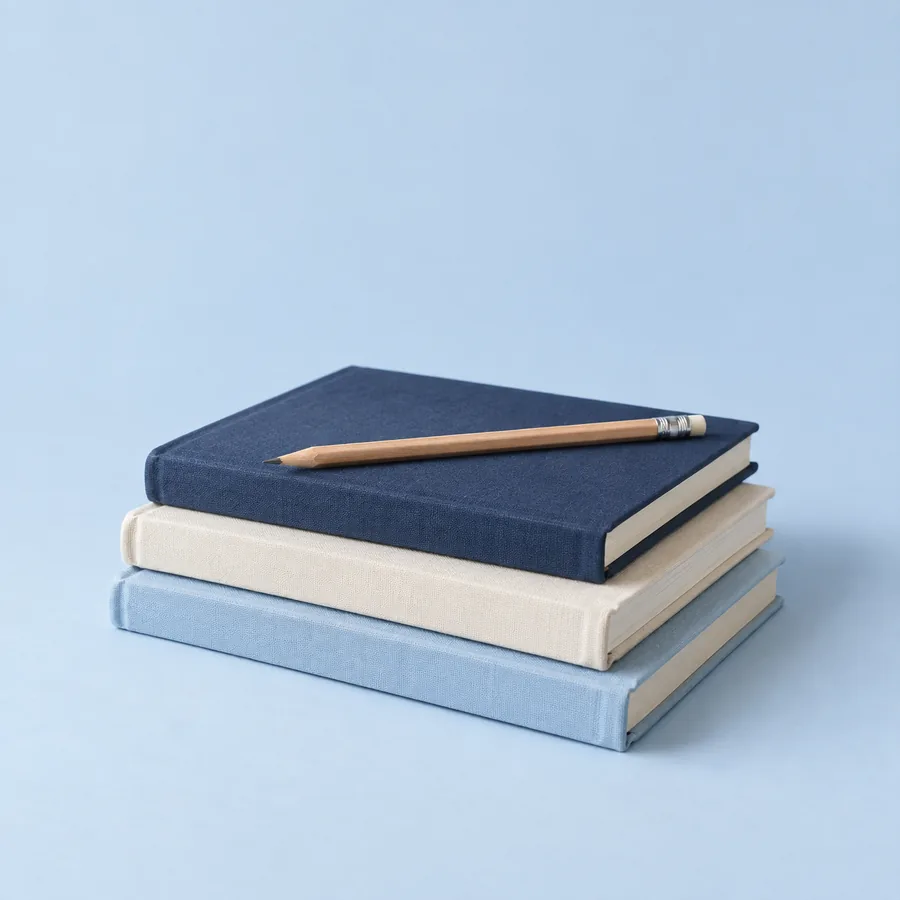 Tumpukan buku bersampul biru dengan pensil di atasnya